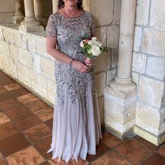 a woman standing next to a wall holding a bouquet of flowers