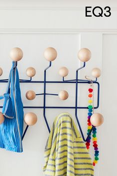 a coat rack with several wooden balls hanging from it's sides and two coats on hooks