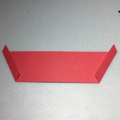 an origami piece of red paper sitting on top of a table