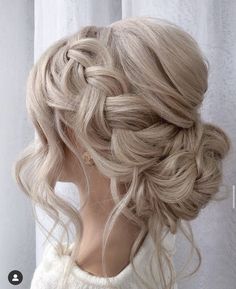 a braided updo with blonde hair is shown in front of a white curtain