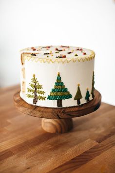 a decorated christmas cake sitting on top of a wooden table next to a white wall