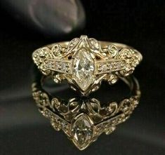 an antique style engagement ring with diamonds on the sides and in the middle, sitting on a black surface