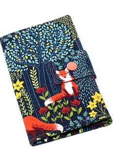 a notebook with an image of a fox in the forest on it's cover