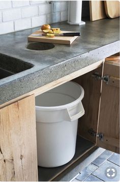 a white bucket sitting on top of a kitchen counter next to a wooden cutting board