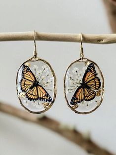 These magical earrings are crafted by systematically placing a delicate Queen Anne's Lace flower and Monarch Butterfly in a resin bezel. The earrings are super light weight and will go perfectly with any outfit! The Pendant and Chain are Lead free and Nickel Free! It is important to preserve the jewelry in the box provided safely after use. Enjoy this necklace with a chain length of your choice. You can see more of my Handmade Items here: https://www.etsy.com/shop/Thecraftiechristie Bohemian Style Resin Flower Earrings As Gift, Whimsical Butterfly Charm Earrings For Gift, Unique Butterfly Earrings For Jewelry Making, Unique Handmade Butterfly Earrings, Nature-inspired Butterfly Earrings For Gift, Monarch Butterfly Necklace, Statement Gold Earrings, Magical Earrings, Queen Anne's Lace Flowers