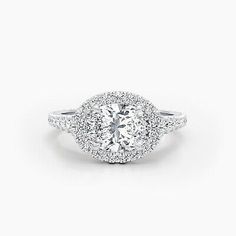 an oval shaped diamond engagement ring with halos on the shoulders and sides, set in white gold