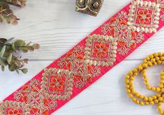 an orange and yellow beaded belt next to some other accessories on a white wooden surface