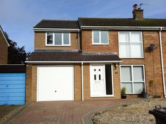 a three story brick house with two garages on the front and one door open