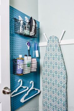 an ironing board is hanging on the wall next to a towel rack and hooks