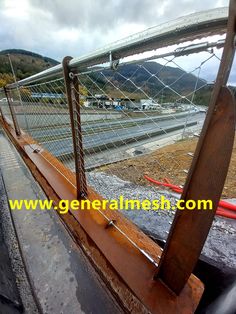 an old wooden boat is sitting on the ground near some water and hills in the background