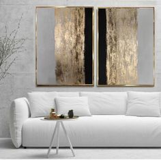 two abstract paintings hang on the wall above a white couch in a modern living room