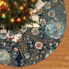 a christmas tree with presents under it on top of a round tablecloth covered in blue and white floral designs