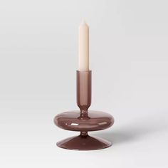 a candle is sitting on top of a glass holder with a white candle in it