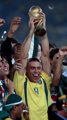 the soccer player is holding up his trophy in front of many other players and fans