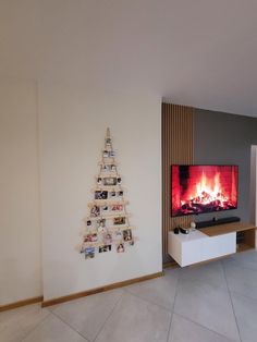 a living room with a christmas tree on the wall and a fire in the fireplace