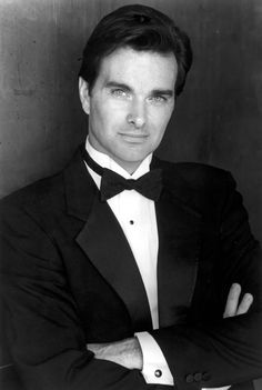 a man in a tuxedo is posing for a photo with his arms crossed