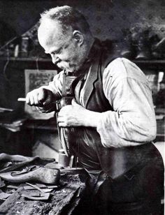 an old black and white photo of a man working on something with a hammer in his hand