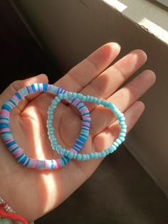 two bracelets in the palm of someone's hand with beads on it,