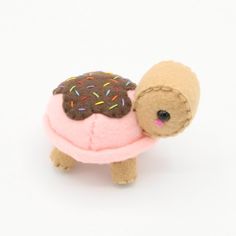 a small stuffed animal with sprinkles and a donut on it's back