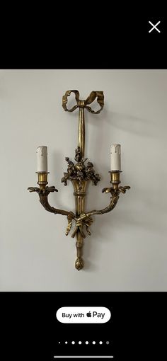 an image of a wall light with two candles attached to the wall and one candle on the wall