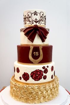 a three tiered wedding cake decorated with red and white flowers, gold trimmings and a brown bow