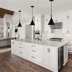 a large kitchen with white cabinets and black pendant lights