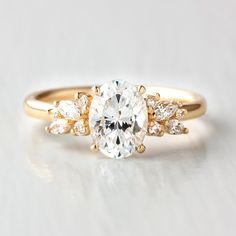 a yellow gold engagement ring with an oval cut diamond surrounded by three smaller round diamonds