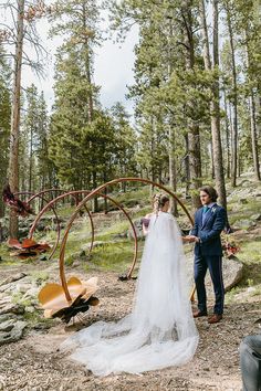 a bride and groom standing in the woods with an arch made out of wooden sleds