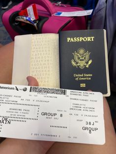 a person holding up a passport and boarding pass in their hand with luggage behind them