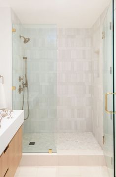 a bathroom with a walk in shower next to a white sink and counter top under a mirror