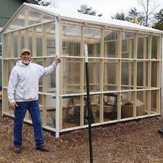 a man standing in front of a small greenhouse