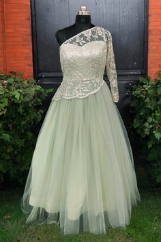 This light Green gown emanates sophistication and grace. Crafted from ethereal net fabric, it showcases a flared silhouette that extends to a majestic floor length. The gown is intricately embellished with sequins, beads, stones, and cutdana, lending it a touch of sparkle and opulence. Featuring a flattering Off -Shoulder at the front and a deeper Off- Shoulder at the back, its Sleeves design adds to its elegance. Equipped with a side zip for ease, this exquisite gown is a perfect ensemble for a Green Organza Dress For Reception, Floor-length Ball Gown With Sheer Bodice, Intricately Embroidered Ball Gown For Prom, Intricate Embroidered Prom Ball Gown, Intricate Embroidery Ball Gown For Prom, Tulle Dresses With Intricate Embroidery And Fitted Bodice, Lace Gown With Sheer Bodice In Maxi Length, Full Length Tulle Gown For Party, Lace Gown With Sheer Bodice, Maxi Length