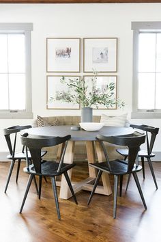 a dining room table with four chairs and pictures on the wall above it that have plants in them