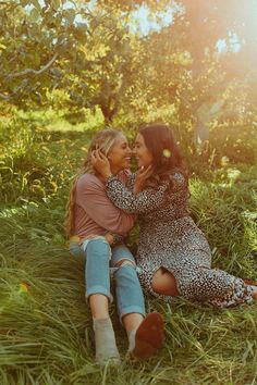 two women sitting in the grass kissing each other