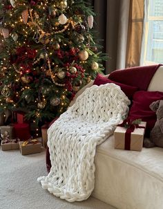 a living room with a christmas tree and presents on the floor, all wrapped up in blankets