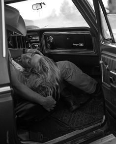 a woman is laying down in the back of a car