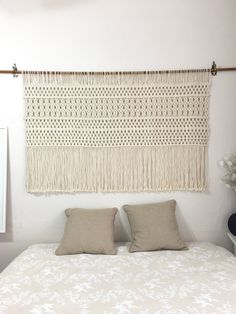 a white bed topped with two pillows next to a wall hanging