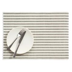 a white plate with two silver forks on top of it next to a striped place mat