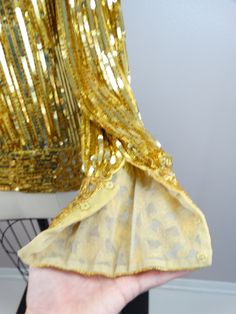 "This beautiful vintage piece is heavily embellished with gold sequins and beading. This piece is very well made and in perfect condition.. absolutely amazing!! Bust - 40\" Shoulders - 18\" Sleeves - 26\" Top Hem to Bottom Hem - 27\" Tag Size - Medium All of my items come from a smoke-free and pet-free home. If you have any questions, please don't hesitate to ask!" Glamorous Gold Dress With Mirror Work, Glamorous Gold Long Sleeve Sequin Dress, Gold Embellished Sequin Dress For Party Season, Gold Sequin Evening Dress For Festive Occasions, Glamorous Fitted Sequin Fabric For Celebration, Gold Embellished Sequin Dress For Wedding, Gold Sequin Dress With Contrast Sequin For Festive Season, Festive Gold Sequin Dress With Contrast Details, Gold Embellished Long Sleeve Sequin Dress