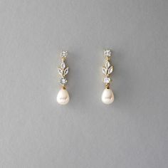 two pairs of pearl and diamond earrings on a gray surface, one with a single drop