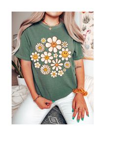 Step into the warmth of style and embrace the carefree vibes with our "Daisy Days Sunshine Bloom Tee." This delightful t-shirt is a celebration of the spirit of warmer days and sunny moments. Crafted from soft, breathable cotton, it provides comfort that matches its sunny disposition. The cheerful design features a vibrant daisy in full bloom, symbolizing the positivity and brightness that comes with the arrival of warmer weather. The playful colors and lively imagery make it a perfect addition Trendy Floral Print T-shirt For Day Out, Green Fun Tops For Day Out, Trendy Smiley Face Tops For Loungewear, Fun Green Tops For Day Out, Trendy Smiley Face Loungewear Tops, Retro Summer Loungewear Tops, Soft-washed Tops For Spring Day Out, Trendy Soft-washed T-shirt For Spring, Hippie Graphic Print Spring Top