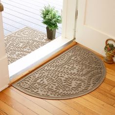 a door mat is on the floor next to a potted plant and an open door