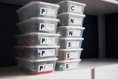 several plastic containers are stacked on top of each other in front of a white shelf