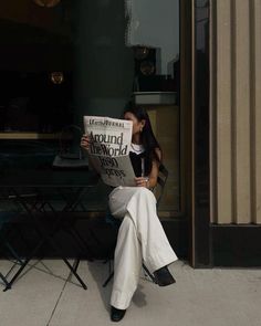 a woman sitting on a chair reading a newspaper