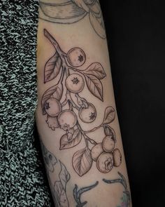 a woman's arm with tattoos on it and fruit hanging from the tree branch