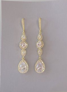 two pairs of gold earrings with white and pink stones on top of each earring