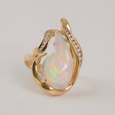 This ring is nothing short of a modern masterpiece.   Materials: 14k Yellow Gold, Australian Crystal Opal, Diamond Weights: 4.71ct Opal, 0.22ct Diamond Size: 7.5 Luxury Exquisite Opal Diamond Ring, Luxury Adjustable Opal Ring As Gift, Luxury Cabochon Opal Ring For Engagement, Luxury Oval Cabochon Opal Ring For Formal Occasions, Modern Diamond White Pear-shaped Ring, Fine Jewelry Yellow Gold Opal Ring With Brilliant Cut, Vvs Clarity Opal Ring For Formal Occasions, Modern Pear-shaped Diamond Ring For Formal Occasions, White Pear-shaped Rings For Formal Occasions