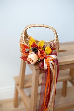 a wooden bench with a basket filled with flowers and ribbons on it's back