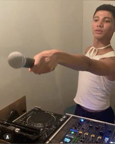 a man holding a microphone next to a dj's turntable