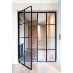 an open glass door leading into a room with wood floors and white walls in the background